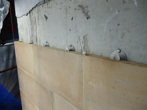 Large limestone veneer slabs directly attached to a concrete substrate using mechanical fasteners